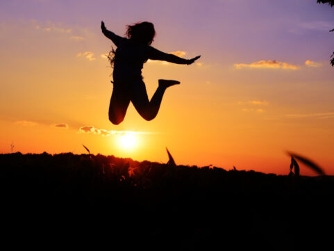 Mensch springt vor lauter Lebensfreude durch die Methode des Qigong beim Ansehen des Sonnenaufgangs in den Himmel